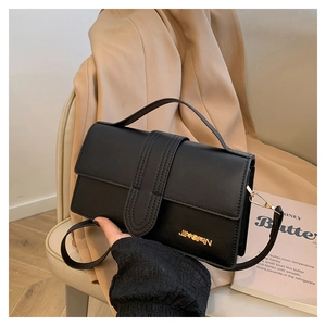 Détail d'un sac à main en cuir noir avec logo doré et rabat à détails texturés