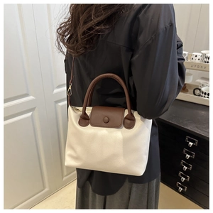 Detail of off-white pillow bag with brown handles showing side view on model indoors