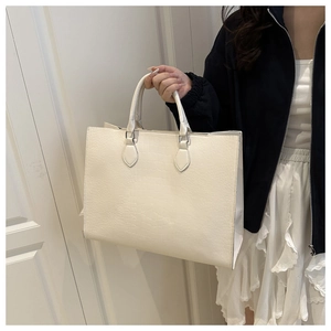 Detail of cream white tote bag with crocodile embossing and dual handle strap design