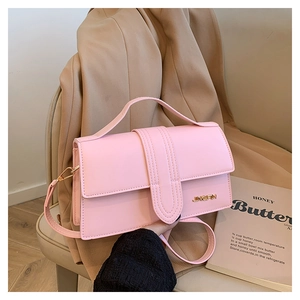 Détail du sac bandoulière en similicuir rose avec logo doré et coutures décoratives
