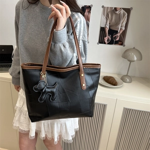 Borsa tote patchwork con manici marroni e ciondolo a forma di cane in un ambiente lifestyle