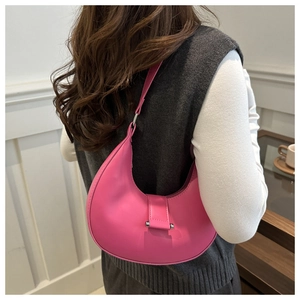 Detailansicht einer magentafarbenen Halbmond-Schultertasche aus glattem Leder am Modell