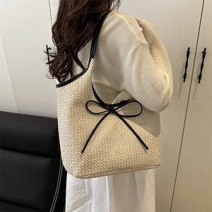 Minimalist beige woven tote bag with black bow detail and leather straps on model