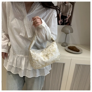 Close-up of cream pillow bag featuring intricate butterfly jacquard and golden shimmer details