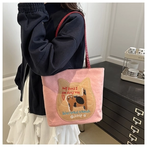 Detailed shot of pink canvas tote bag with red handles and embroidered cat patch
