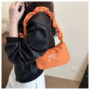 Orange small shoulder bag featuring bow embroidery and trendy ruched strap on a model