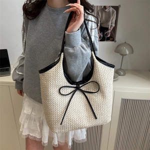 Stylish beige woven straw tote bag with black bow details and handles for women