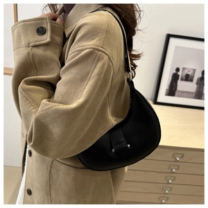 Minimalistische schwarze Halbmond-Tasche mit silbernen Details an der Schulter getragen