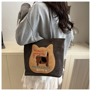 Detailed embroidery on a charcoal grey tote bag featuring cat pattern and text details