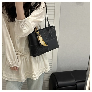 Detail of black tote bag with croc-embossed leather, white stitching, and silk scarf wrap