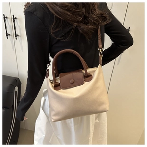 Detail of cream and brown pillow bag with lychee texture leather and gold hardware
