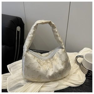 Detail of cream pillow bag featuring golden butterfly patterns and pearl silk texture