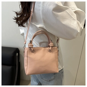 Detail of light pink leather square crossbody bag with textured pebble finish