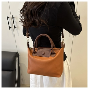 Brown lychee texture leather satchel with adjustable strap shown on a model