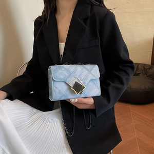 Sac bandoulière en denim bleu clair avec boucle dorée géométrique sur modèle