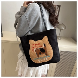 Detail of black suede tote bag featuring a large cat patch embroidery and leather straps