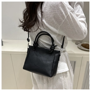 Detailed back view of a black litchi pattern leather crossbody bag worn by a model