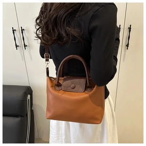 Detail view of caramel and brown leather pillow bag with adjustable strap and gold hardware