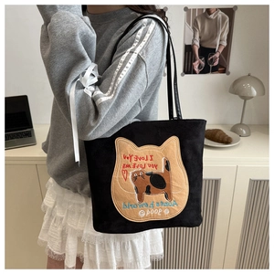 Detail of a black tote bag featuring a cat illustration and I Love You embroidery