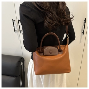 Detail of premium textured leather dumpling bag with brown color-blocking and gold hardware