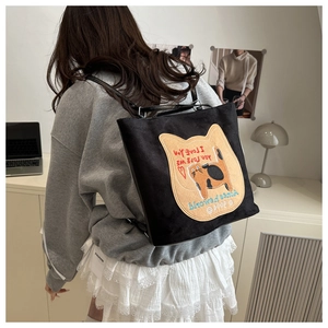 Detailed back view of a black canvas tote bag with orange cat embroidery and shoulder straps