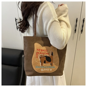 Detail of a brown suede tote bag featuring a cute cat patch and I Love You embroidery