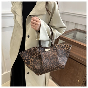 Detail view of leopard print tote bag with gold logo plaque and textured dual handles