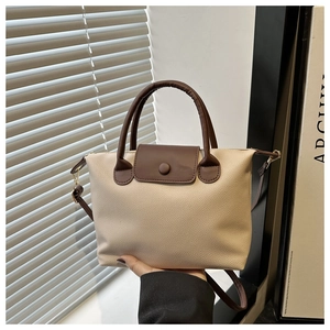 Detailed close-up of beige lychee grain leather tote bag with dark brown handles and straps