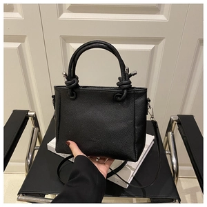 Detail of black lychee grain leather square tote bag with silver hardware and top handle
