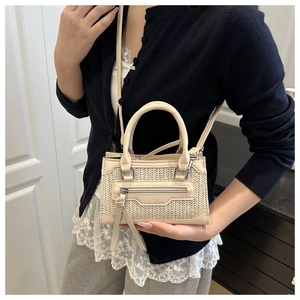 Dettaglio mini borsa a mano in tessuto color crema con frange e tracolla sottile