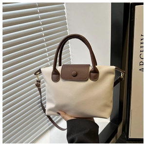 Detail of contrast stitch tote bag with lychee texture and brown handle in studio setting