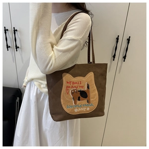 Detail of brown tote bag with cat patch embroidery and casual shoulder strap design