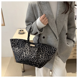 Detailed view of leopard print tote bag with metallic logo plate on canvas material