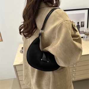 Minimalistische schwarze Halbmond-Umhängetasche kombiniert mit einer khakifarbenen Jacke