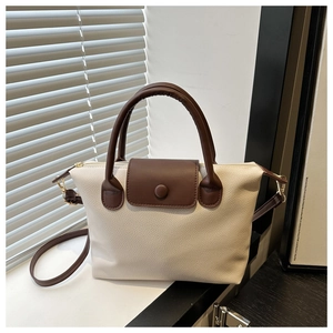 Detail of cream and brown pillow bag featuring litchi texture PU leather and top handle