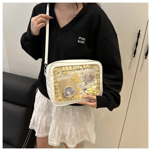 Detail of white PU ita bag showing transparent window with yellow ribbons and badges