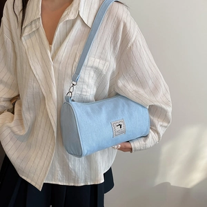 Blue canvas cylinder crossbody bag with cartoon dog patch and wide shoulder strap
