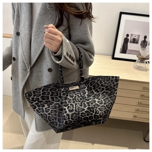 Detail of leopard print tote bag with metal buckle shown in minimalist home setting
