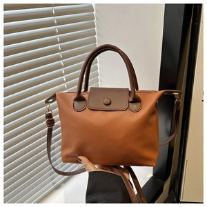 Close-up of caramel lychee texture leather handbag with brown contrast handles and hardware