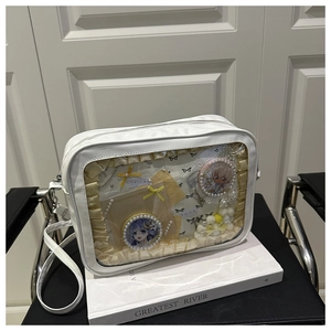 Detail of white PU Itabag showing transparent window with lace and anime badges
