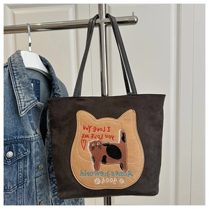 Detail of suede tote bag featuring colorful cat embroidery and stylish script patterns