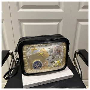 Detail of black ita bag featuring a large clear window with anime badges and ruffled trim