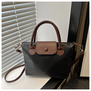 Detail of a black and brown leather dumpling bag with lychee texture and stitching