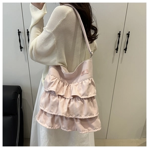Detail of pink ruffled hobo bag showing layered frills and satin texture on model