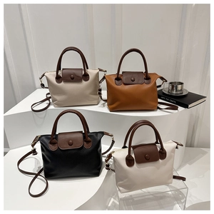 Detail view of multi-color leather trapezoid bags with contrast handles and flap closures