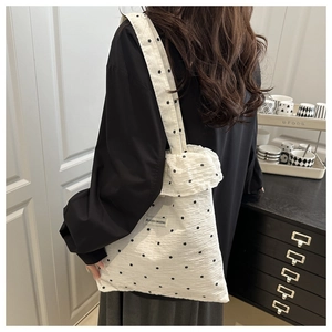 Détail du sac cabas blanc à fleurs en tissu plissé porté par un mannequin femme