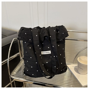 Détail du sac cabas en toile noire à motif floral blanc avec étiquette logo
