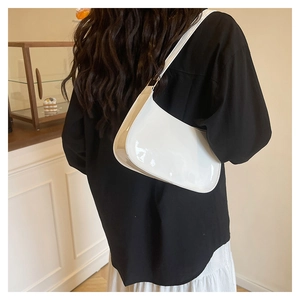 Close-up of white glossy patent leather shoulder bag on a female model for daily styling