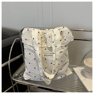Gros plan du sac cabas plissé blanc avec petits motifs floraux noirs et étiquette