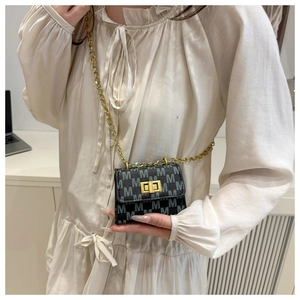 Detail of mini black square bag with M-letter print, gold chain and twist lock